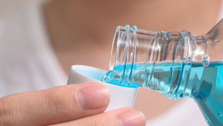 Hand of man Pouring Bottle Of Mouthwash Into Cap.jpg