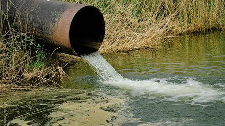 Wastewater pouring out of a tube into a river.