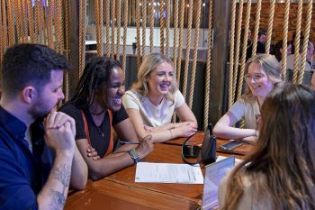 Group of smiling people at a table conversing over quiz answer